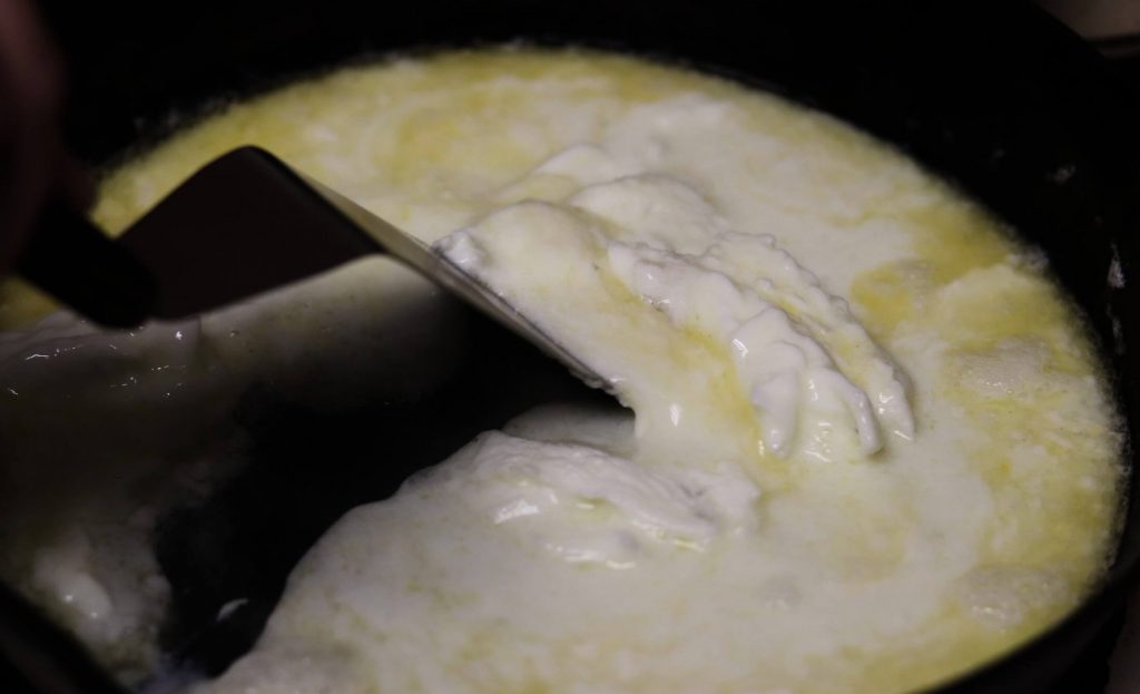 closeup of inside of frying pan with 8 ounces of egg whites starting to coagulate with a spatula scraping them from the pan in the center of the pan