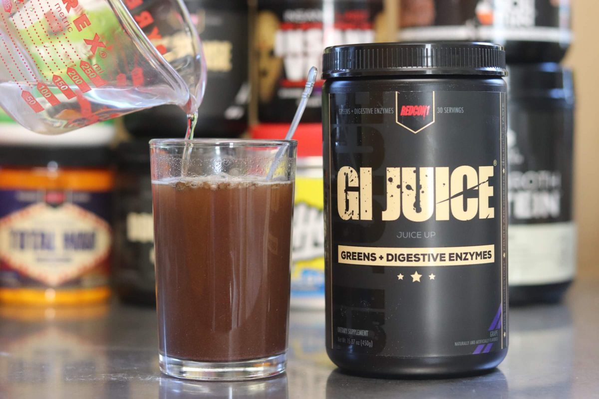 tub of redcon1 gi juice greens and digestive enzymes next to a glass with brownish mixture of water and gi juice powder with measuring cup pouring in water
