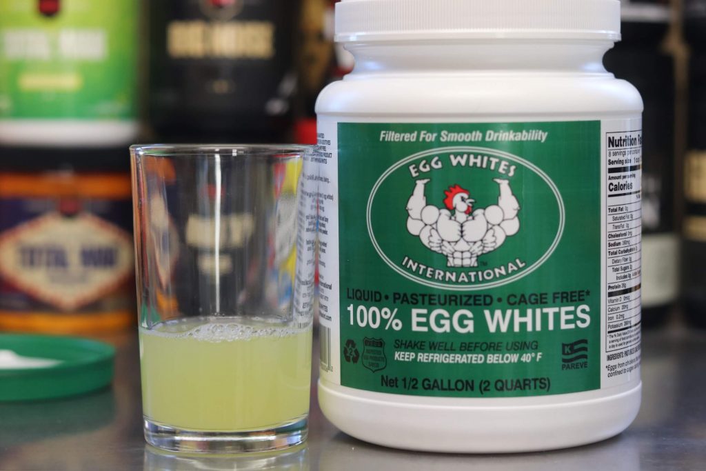 half gallon tub of egg whites international liquid egg whites with green label with muscular cartoon chicken, tub is next to glass filled with 4 ounces of liquid egg whites