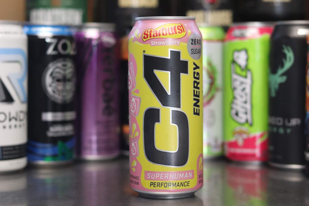 closeup of c4 energy starburst strawberry can in pink and yellow with background of 8 other energy drink brands