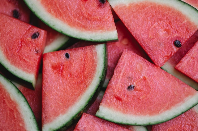 closeup of slices of bright pink watermelon with black seeds and green rind