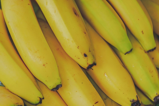 closeup of bottom half of bunches of bananas that are yellow with hints of green