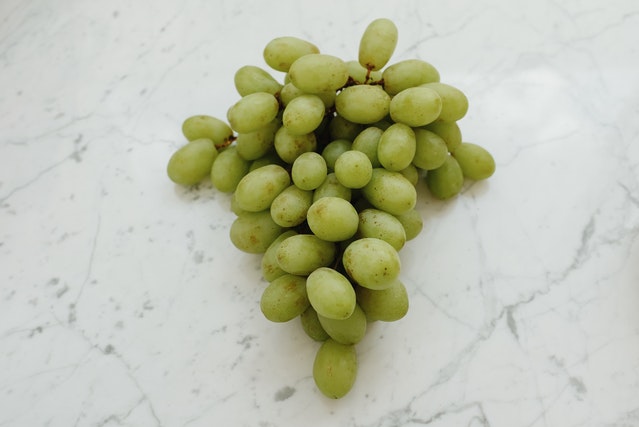 bunch of green grapes sitting on a granite countertop