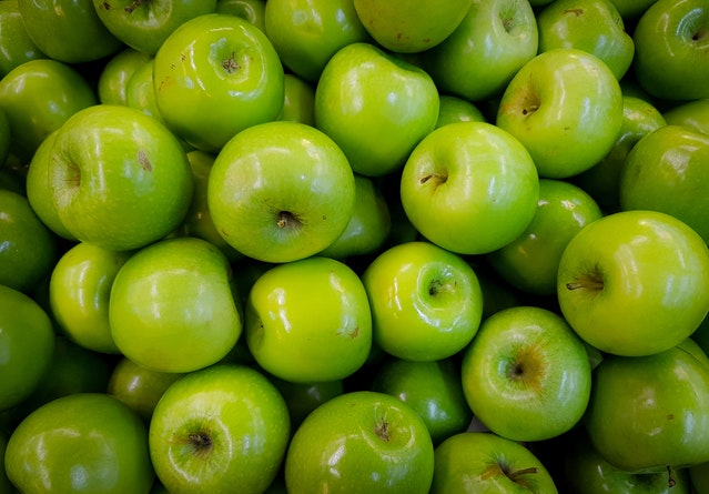 closeup of pile of about 40 shiny green apples