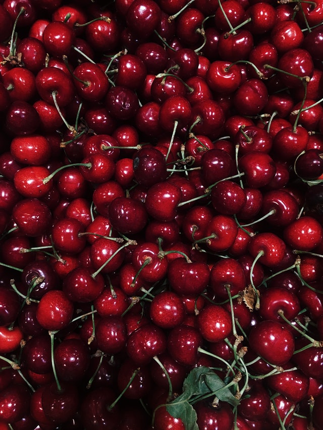 pile of hundreds of red cherries with stems